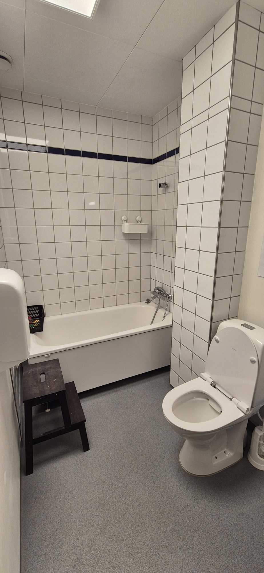 Badeværelse ned hvide fliser, toilet og badekar