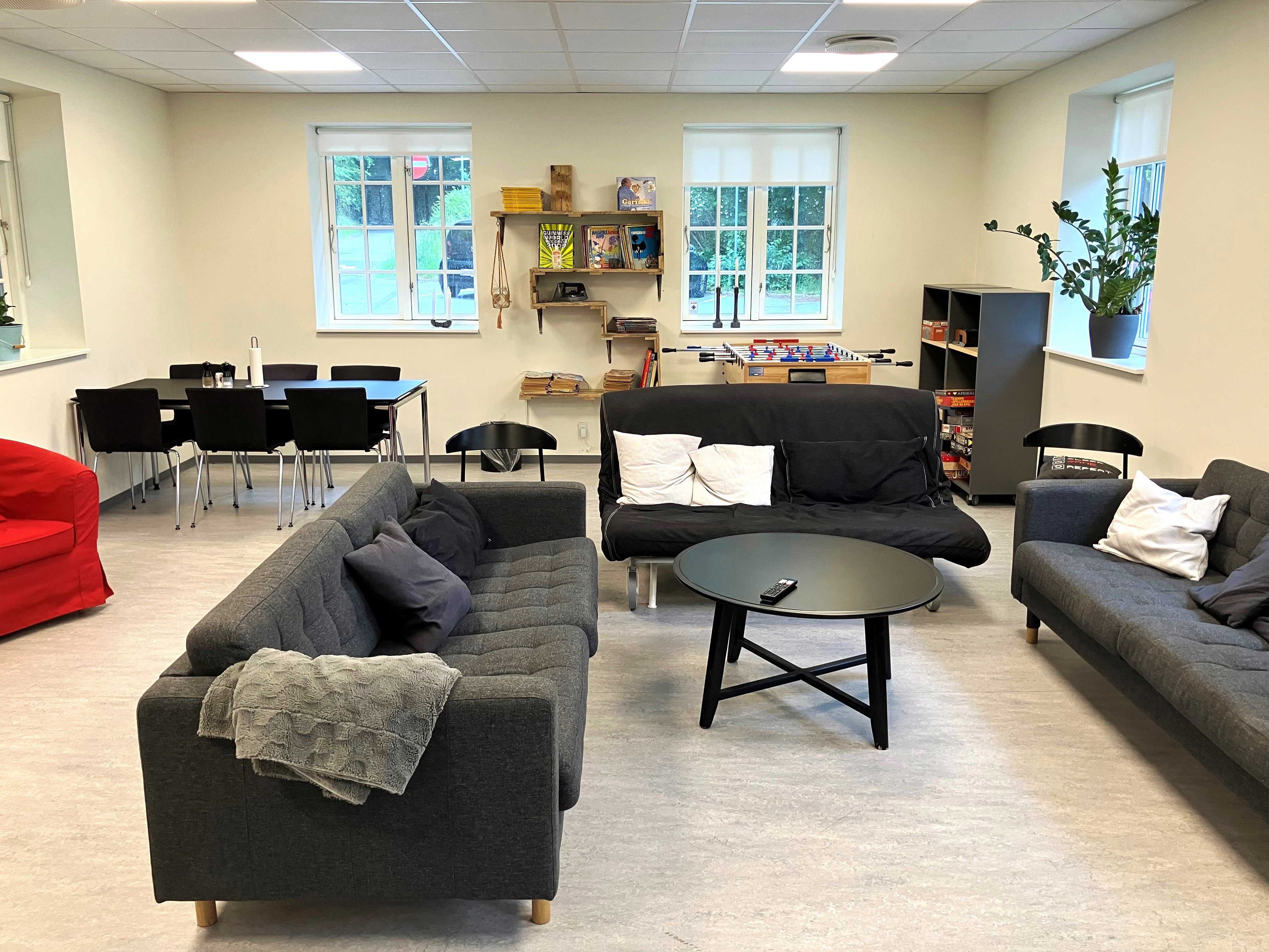 Opholdsstue med grå sofaer, bordfodboldbord og spisebord