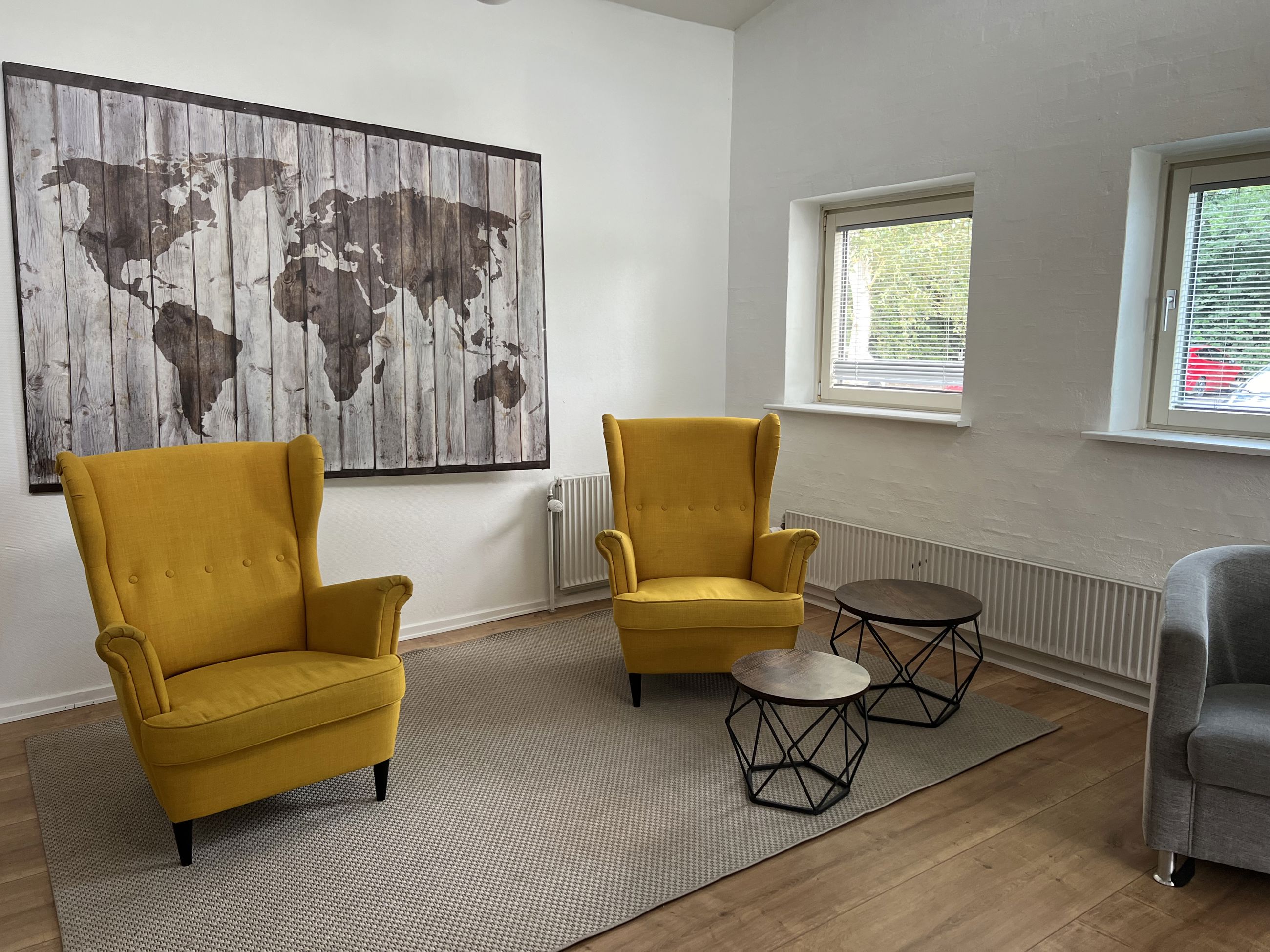 Engen Fællesstue med to gule lænestole og verdenskort på væggen
