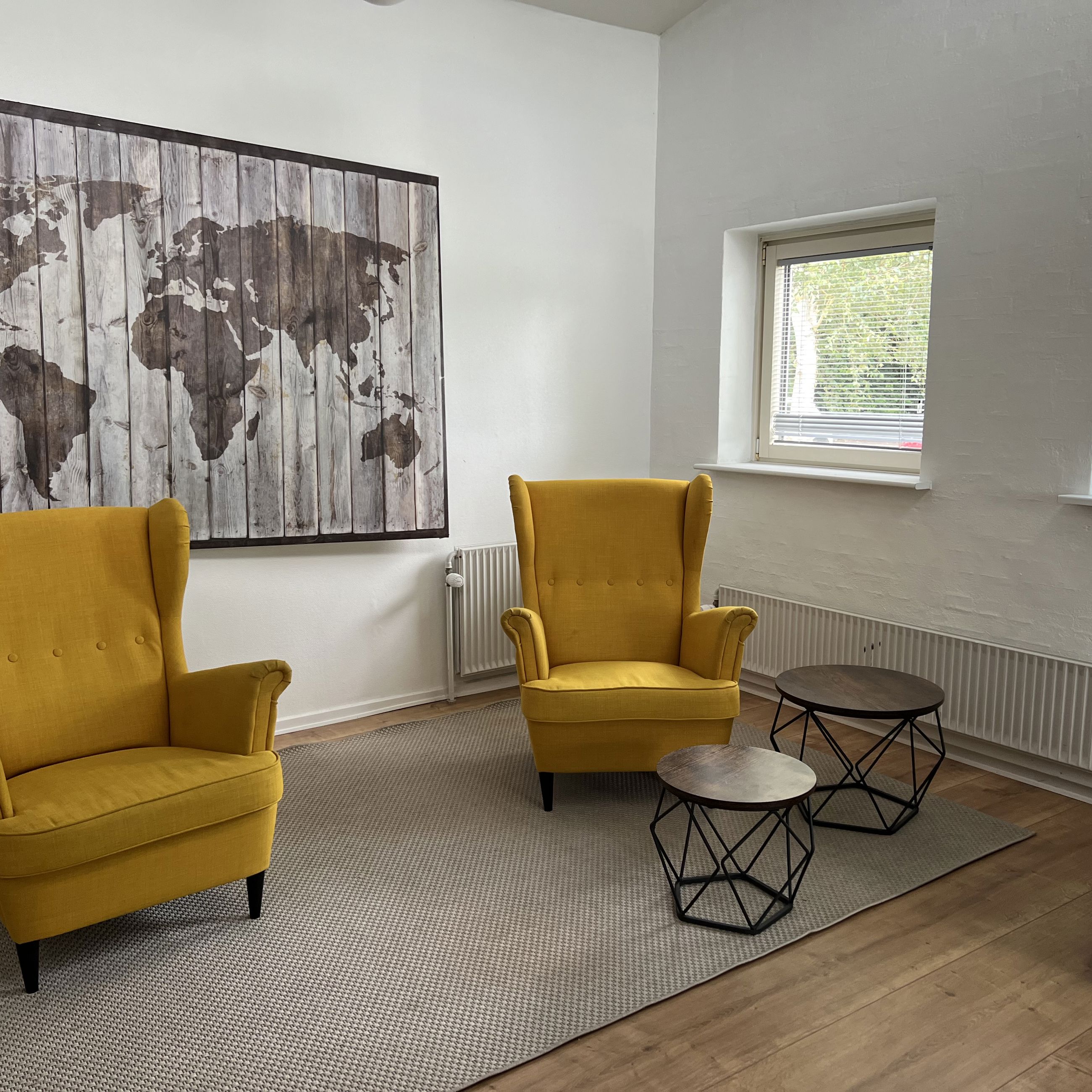 Engen Fællesstue med to gule lænestole og verdenskort på væggen