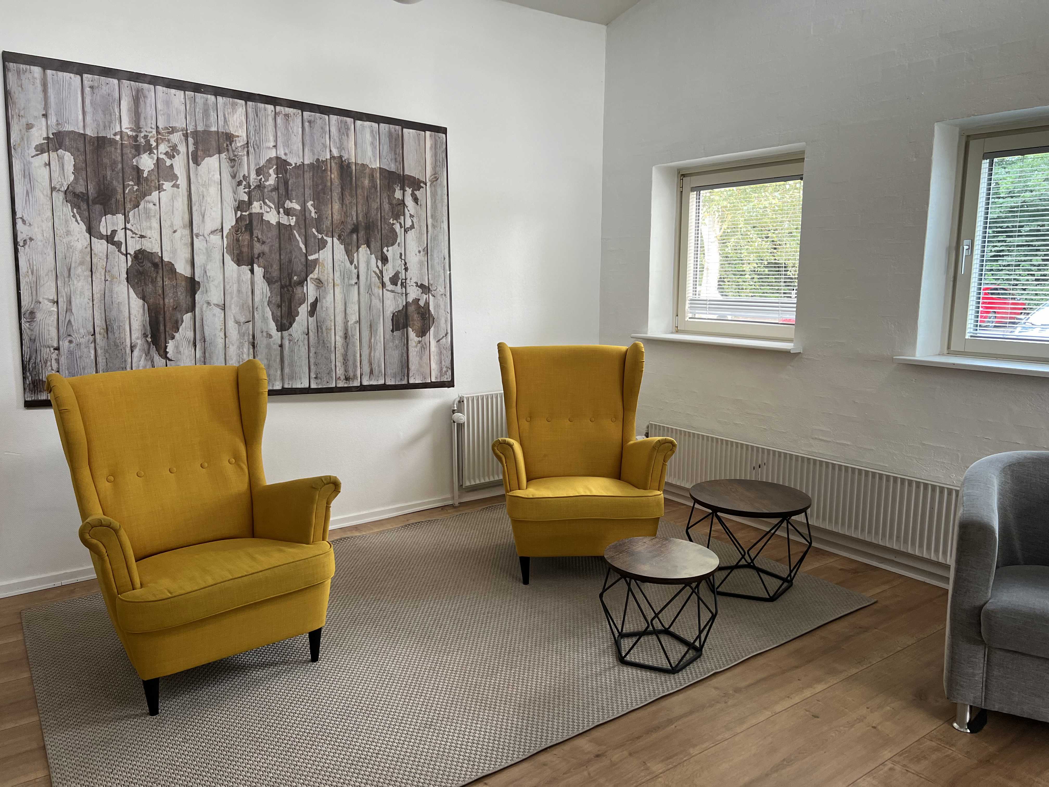 Engen Fællesstue med to gule lænestole og verdenskort på væggen