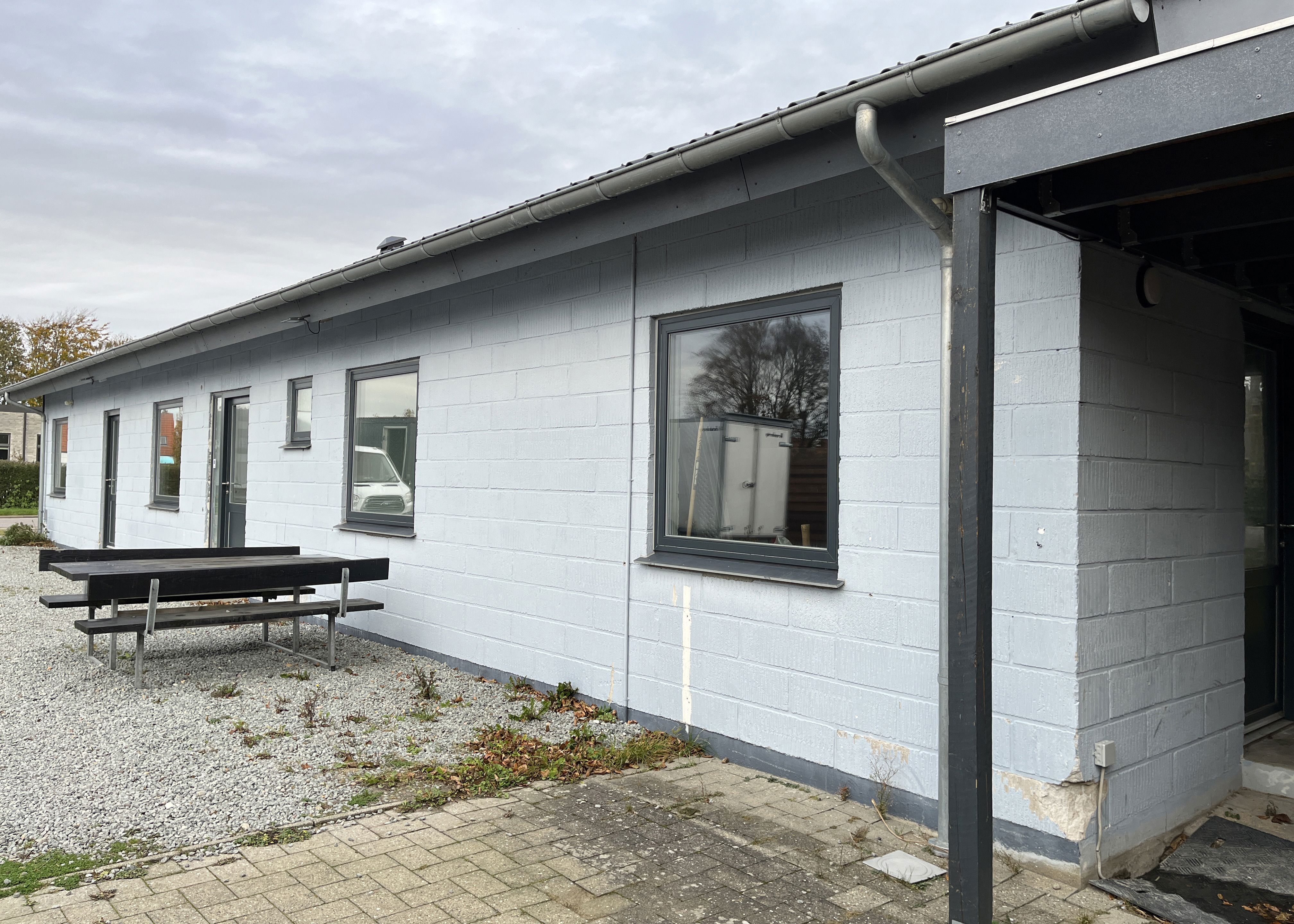 Hvid bygning med bordebænkesæt foran