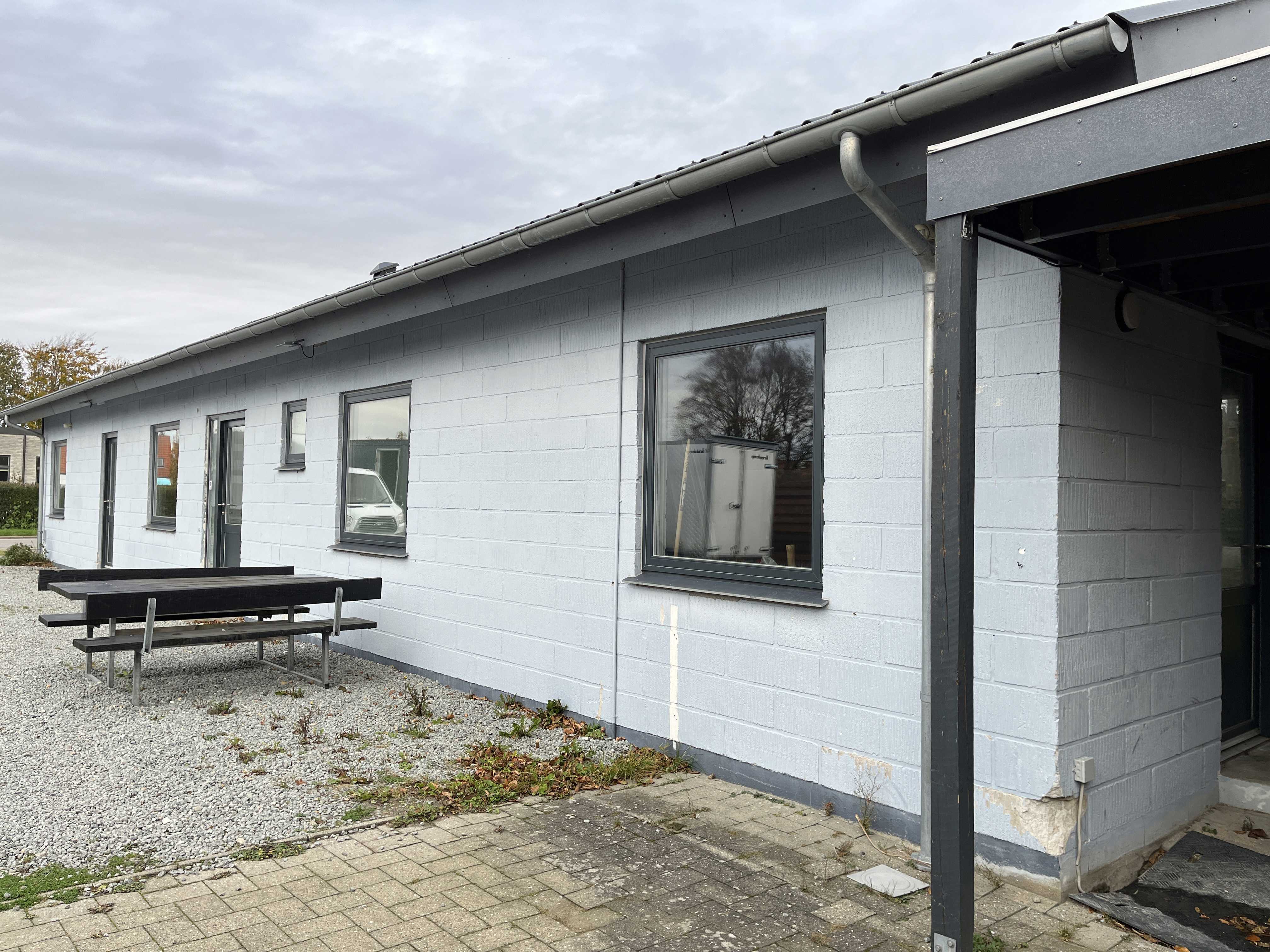 Hvid bygning med bordebænkesæt foran