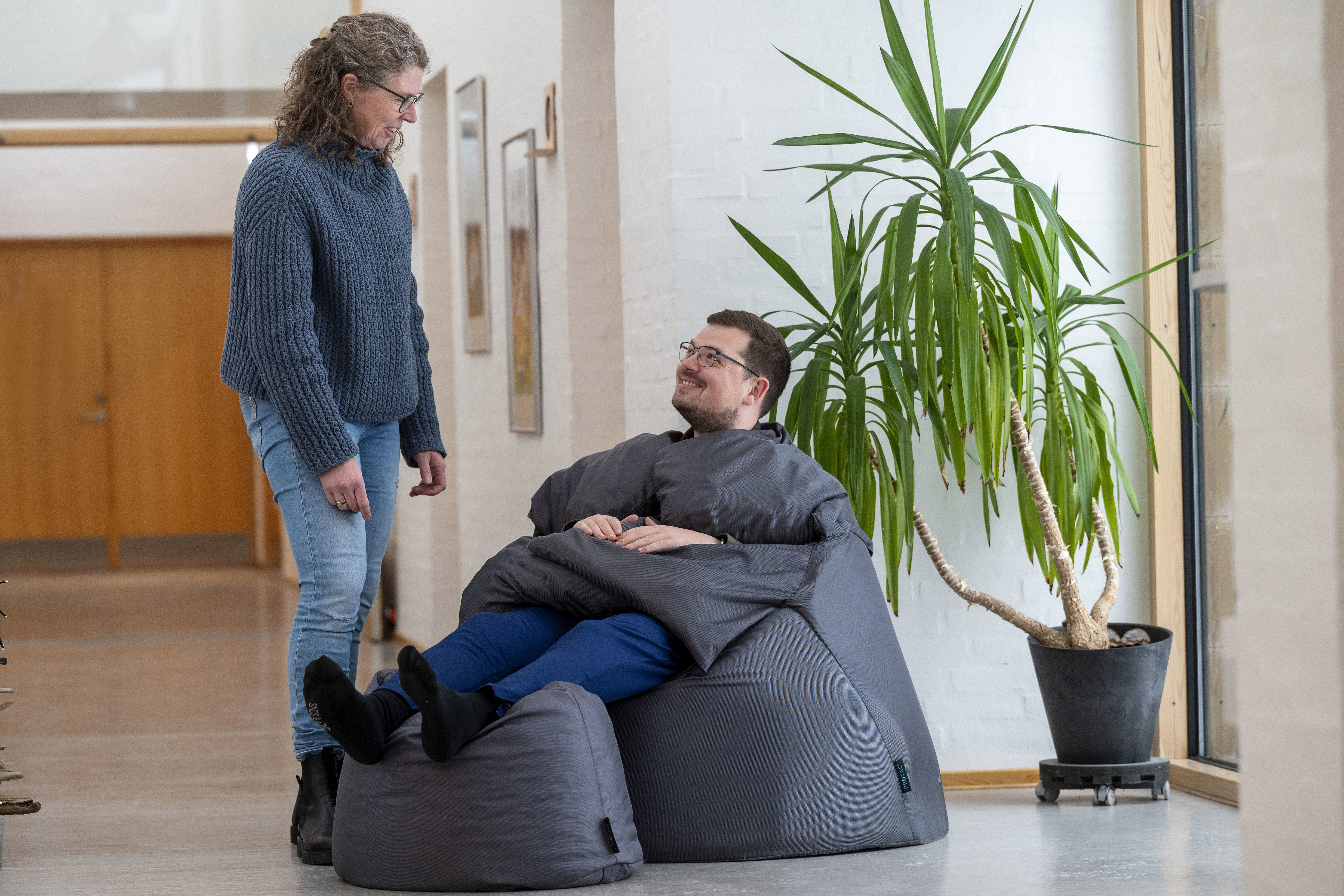 En borger i en sækkestol og en fagperson kigger på ham